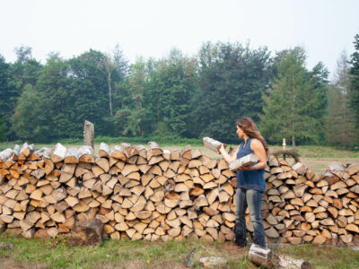 woman stacking firewood in field to dry